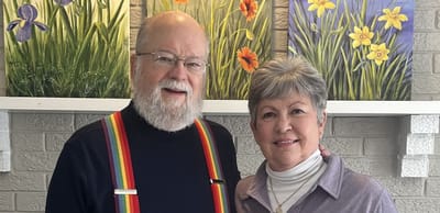 Two residents smiling in a common area with flower paintings