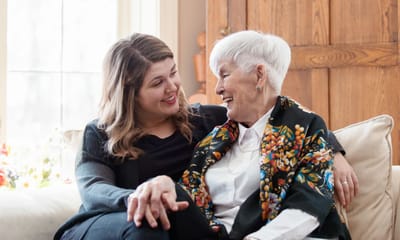 A caregiver interacting joyfully with a senior resident in a cozy living space.