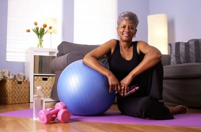Meadowcrest – Middletown, Assisted Living in Middletown, DE — Woman exercising with a stability ball and weights in a bright room