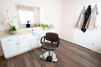 A clean hair salon area with styling chair and mirrors