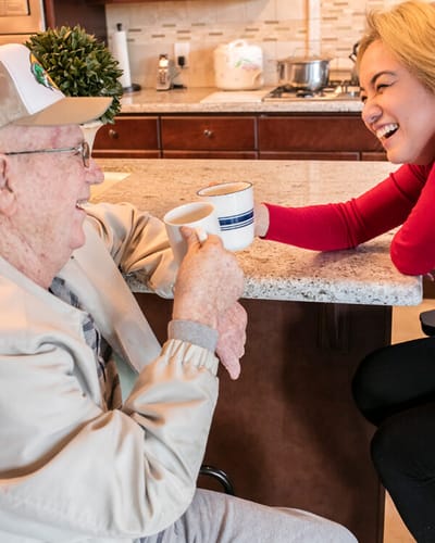 Resident enjoying coffee with staff in a cozy kitchen