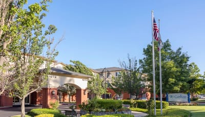 Exterior view of a senior living facility with entrance and flags