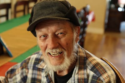 A smiling elderly man in a cozy indoor setting