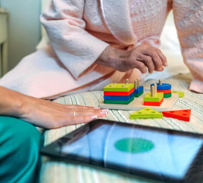 A close-up of an elder playing with colorful building blocks