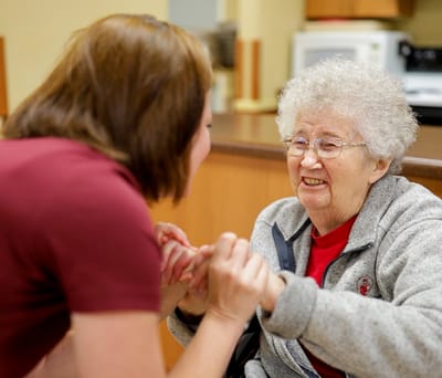 A caregiver interacting with a resident in a bright interior setting.