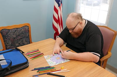 Resident coloring at a table with colored pencils