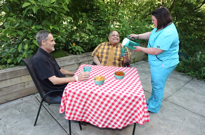 Residents enjoying refreshments outdoors with staff