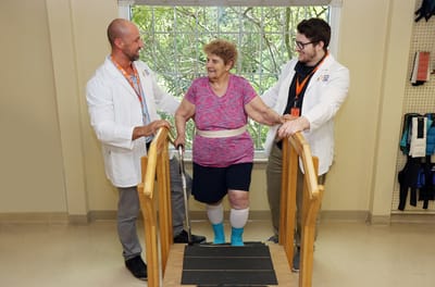 Therapists assisting a resident on a rehabilitation step