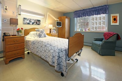 A well-furnished resident room with a bed and chair