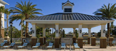 Outdoor pavilion with seating and palm trees.