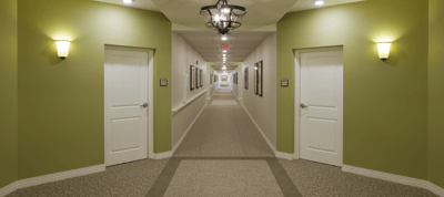 Brightly lit corridor with doors and framed pictures