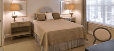 Well-furnished resident room with a bed and lamps