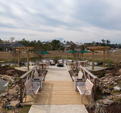 Outdoor seating area with benches and tables by a pond