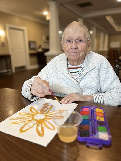 Resident painting flower art during an activity session
