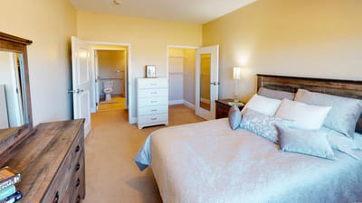 A well-furnished private resident room with a bed and dresser