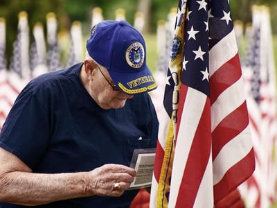 Veteran paying respects at a memorial with flags