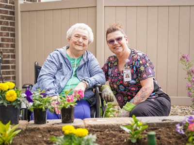 Resident and staff member gardening outdoors