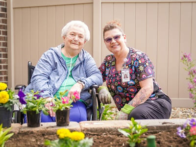 Resident and staff member gardening together in an outdoor space