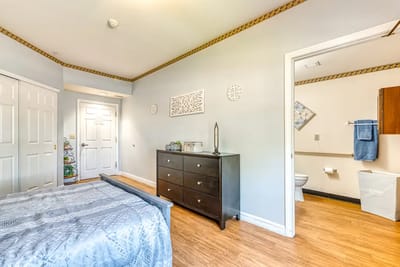 A well-furnished resident room with a bed and dresser