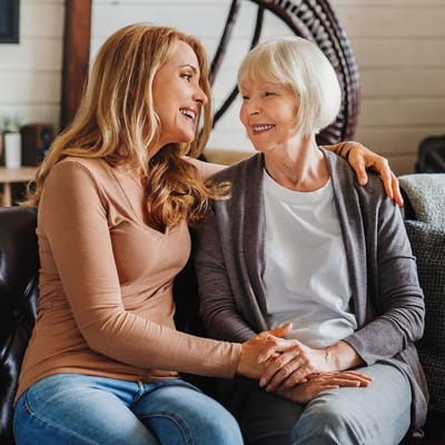 A caregiver and a resident smiling together on a couch