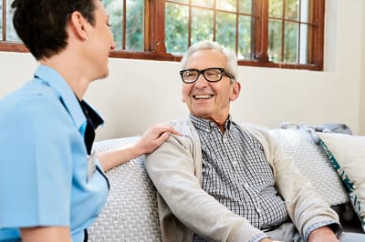 A caregiver and resident smiling together indoors