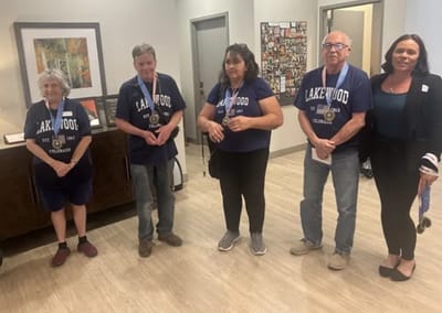 Residents and staff posing with medals in an interior common area