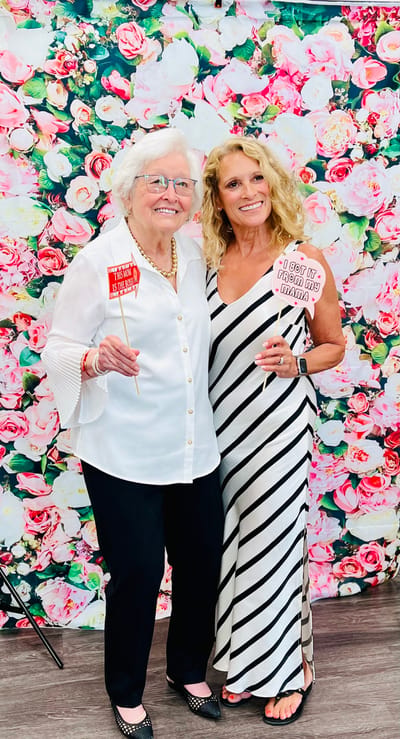 Two women enjoying a celebratory event with playful signs