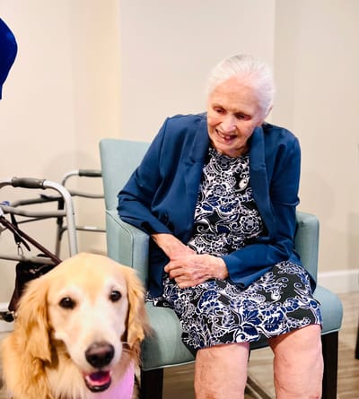 Resident sitting with a therapy dog in a cozy environment