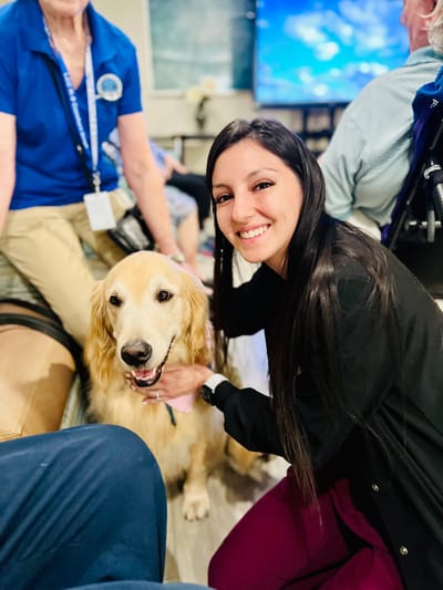 Staff member and resident interacting with a therapy dog