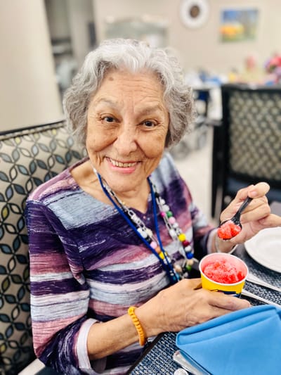 A senior resident enjoying a treat in the dining area