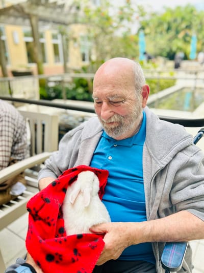 A resident holding a rabbit outdoors, enjoying the sun