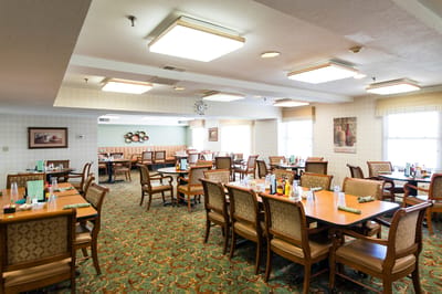Dining room with tables and chairs set for meals.