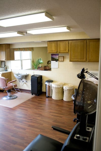 Hair salon area with styling chair and storage.