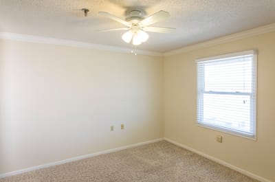 Empty resident room with beige walls and carpet.