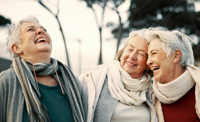 Three smiling elderly women enjoying time outdoors