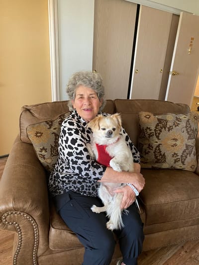 Senior woman holding a small dog on a couch