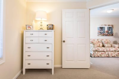 Bright interior space with a dresser and floral couch.