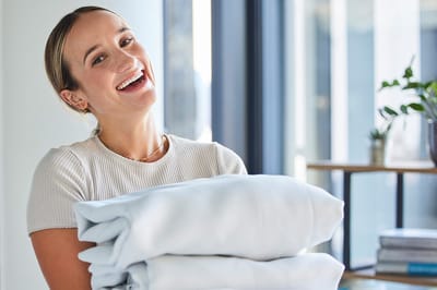 Staff member smiling while holding clean linens.