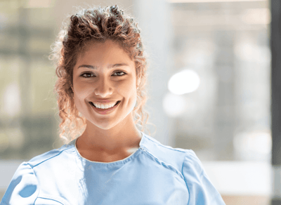 Nurse smiling in a bright interior space.