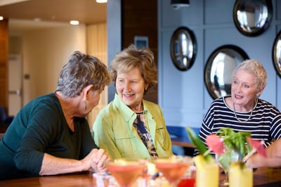 Three residents enjoying conversation in a common area.