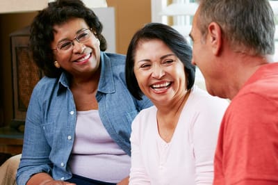 Three smiling residents enjoying conversation in a common area