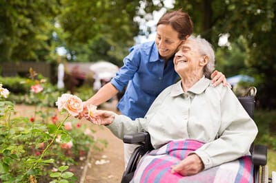 Resident enjoying flowers with staff in a garden