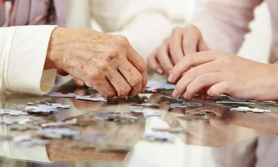 Hands of residents and staff working on a puzzle