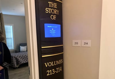 Interior hallway with room numbers and a display screen.