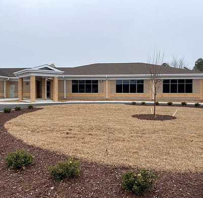 Exterior view of the facility building with landscaped area.