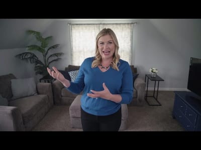 A woman presenting in a living room setting.