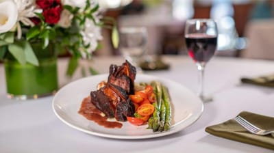 Plated meal with vegetables and wine in elegant dining setting.