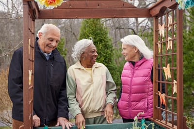 Three seniors enjoying time in a garden space.