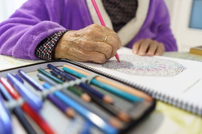 Elderly person coloring in a book.