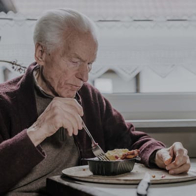 Elderly man enjoying a meal indoors.